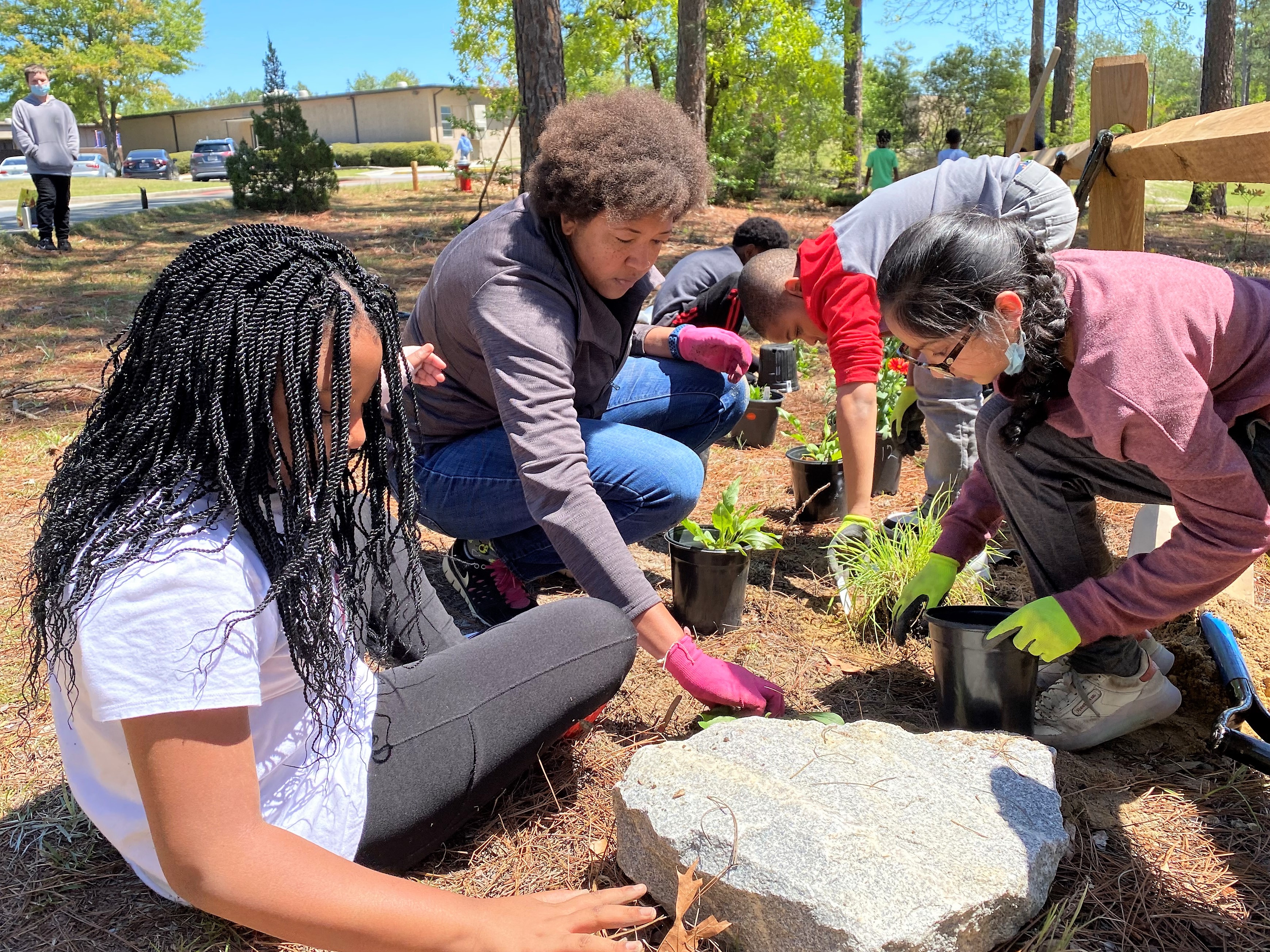 Students work with an adult to plant native plants in a Carolina Fence Garden