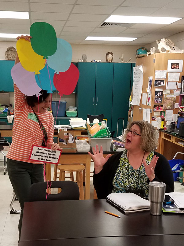 Amy Umberger (right) is surprised with a bouquet of paper balloons